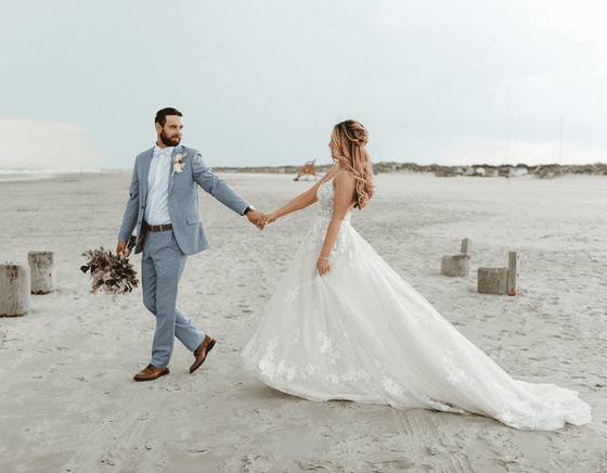 A newlywed couple walks together on the beach at our Diamond Beach wedding venue