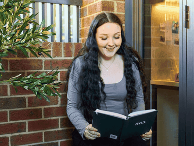 A smiling woman reading a book at UniLodge Royal Melbourne.