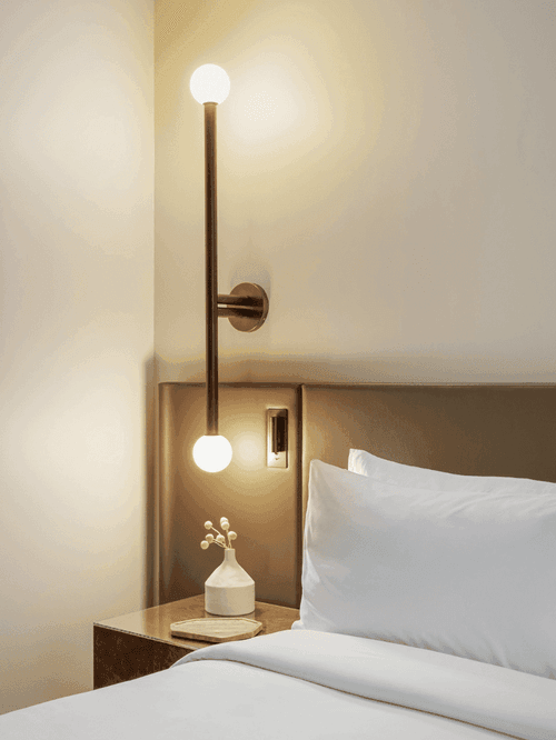 Hotel bedroom with white bedding, framed artwork, bedside lamp and wooden headboard detail