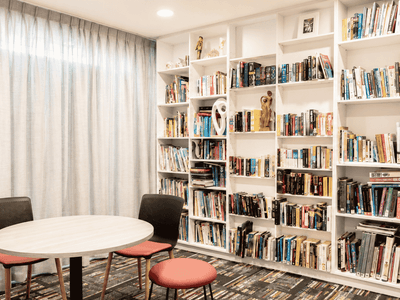 Bright study area with white bookshelves, round table, and coral seating at Student Living - Waymouth