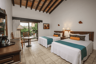 A hotel room with two beds, a coffee maker, a table, chairs, and a balcony with an outdoor view.