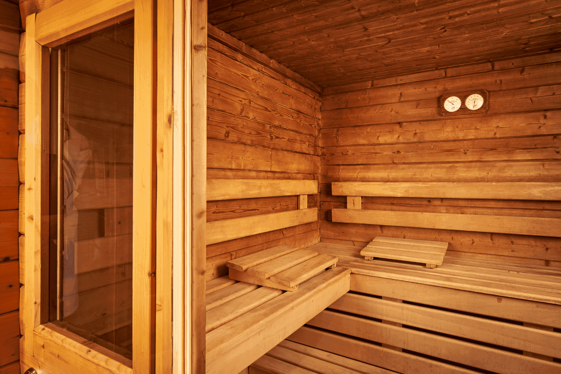 Interior of a wooden sauna with thermometer placed by benches under warm ambient lighting at Hotel Westminster Paris