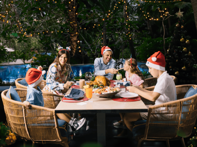 A family gathered around a table adorned with Christmas decorations, enjoying a festive meal together.