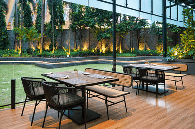 Outdoor dining area with wooden interior next to the garden in Cinnamon Coffee House at One World Hotel