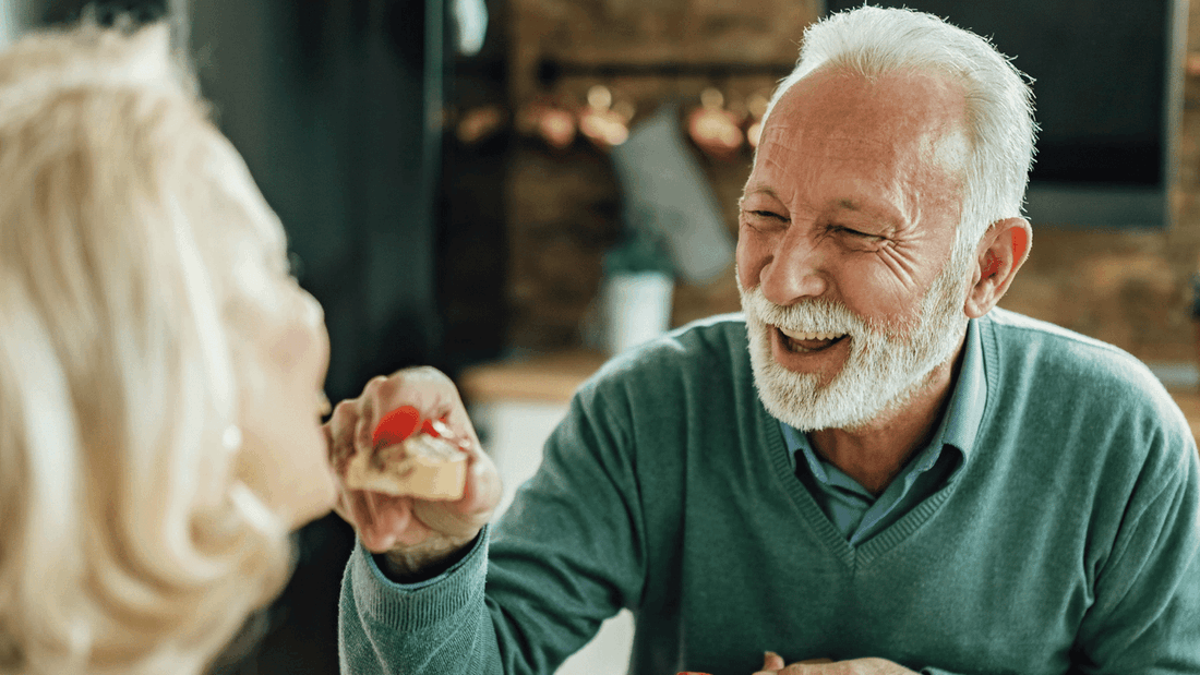 Senior man laughing while being fed a snack by a woman at Novotel Sydney International Airport
