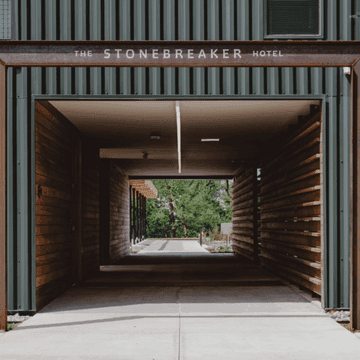 The Stonebreaker Hotel entrance shows a corridor with wooden walls and a bright outdoor view.