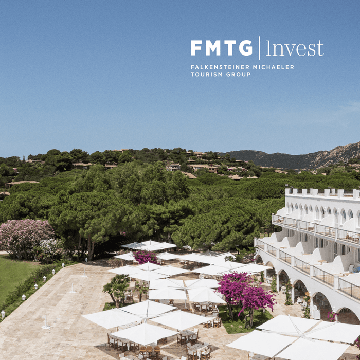 Hotel mit weißen Schirmen und gepflastertem Hof vor grüner Landschaft bei Falkensteiner Michaeler Tourism Group