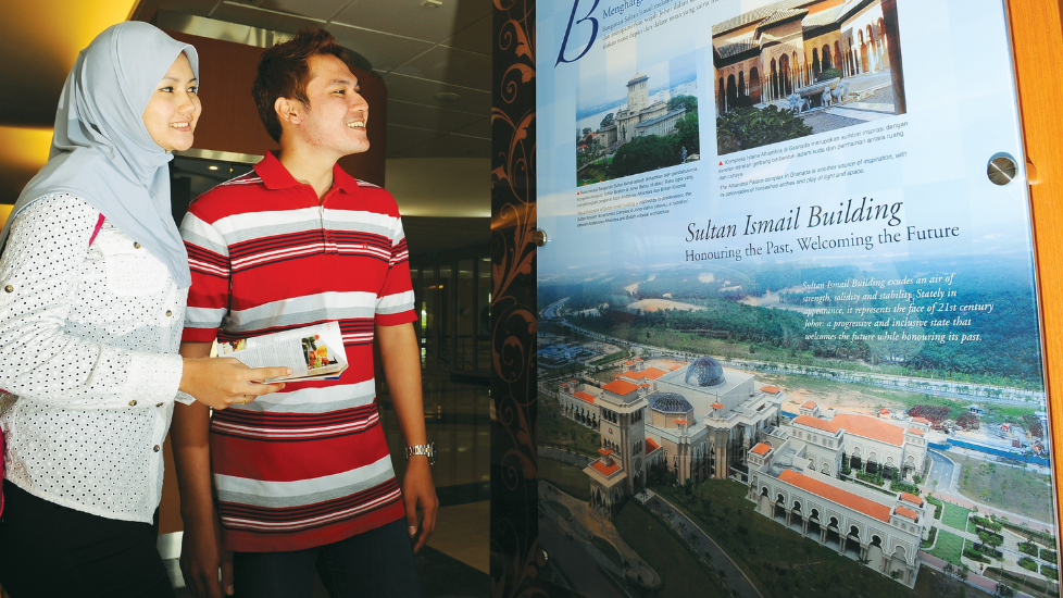 Couple looking at a poster of Dataran Mahkota, Kota Iskandar near Sunway Hotel Big Box