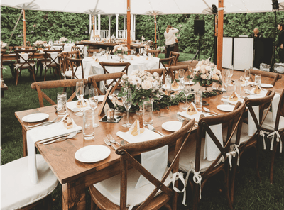 Outdoor reception tent with long wooden tables and floral centerpieces, a romantic wedding venue at The Exeter Inn