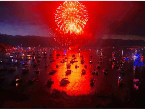 Boats illuminated with red and blue lights during Two Harbors Fireworks Motor Tour.
