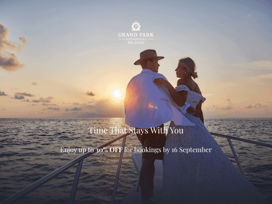 A couple embraces on a boat deck at sunset over the ocean, with golden light illuminating the romantic scene.