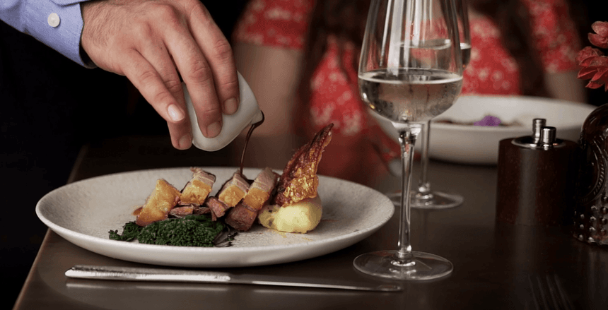 Man pouring gravy over roasted meat dish