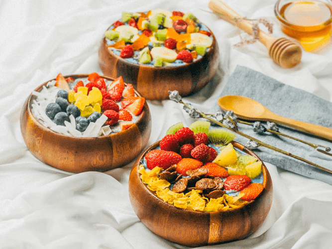 Three bowls filled with an assortment of fresh fruit and drizzled honey, showcasing vibrant colors and textures.