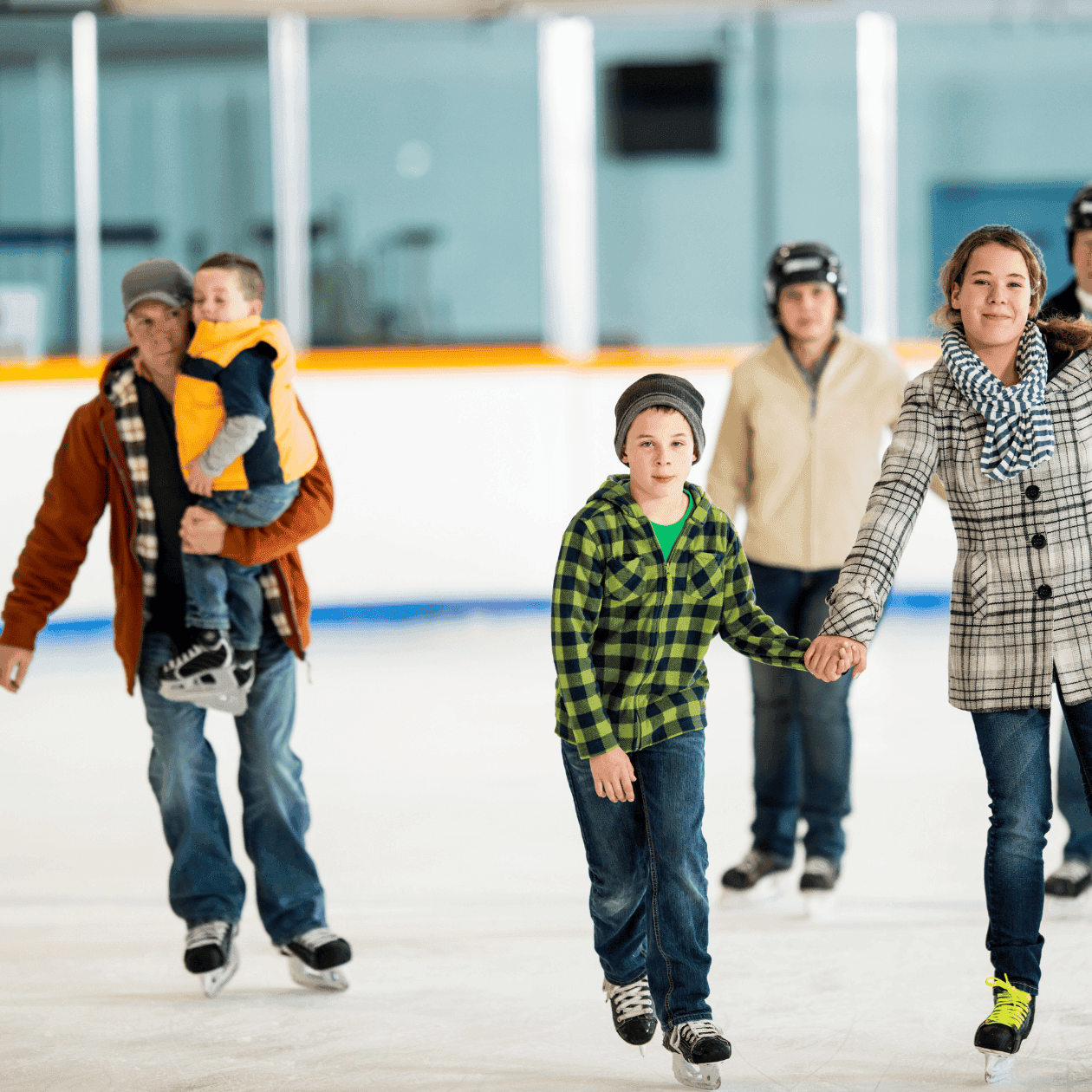Families enjoying ice skating together at an indoor rink.