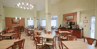 Breakfast area with wooden tables and chairs under a chandelier at Galleria Palms Hotel
