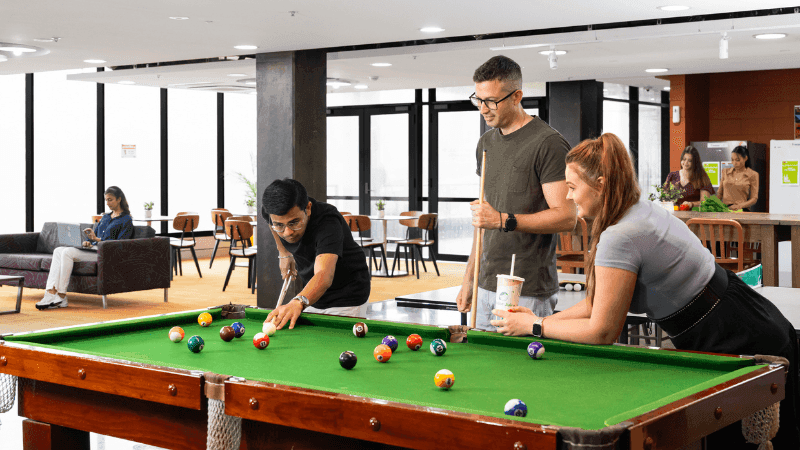 People playing pool in a hotel lobby with other guests at StudentLiving Darwin.