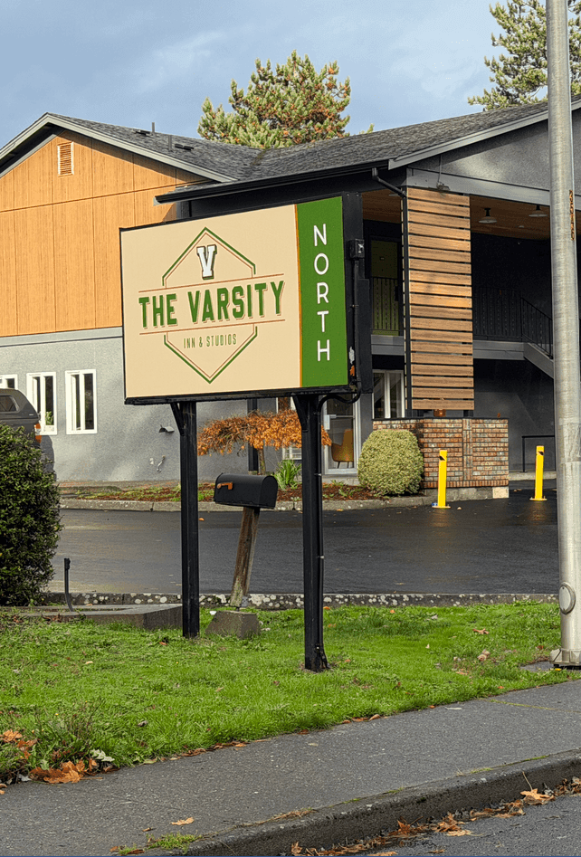 Hotel entrance with The Varsity North sign, surrounded by green grass and bushes, one of the luxury Centralia, WA hotels