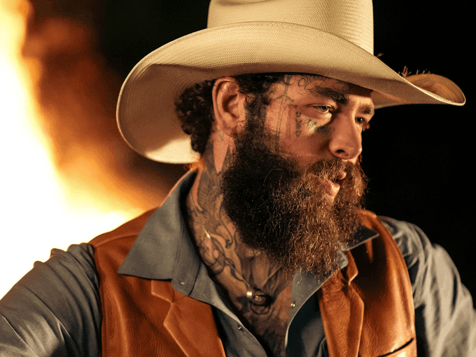 Post Malone wearing cowboy hat and vest with tattoos on his face for The BIG ASS World Tour 2026.