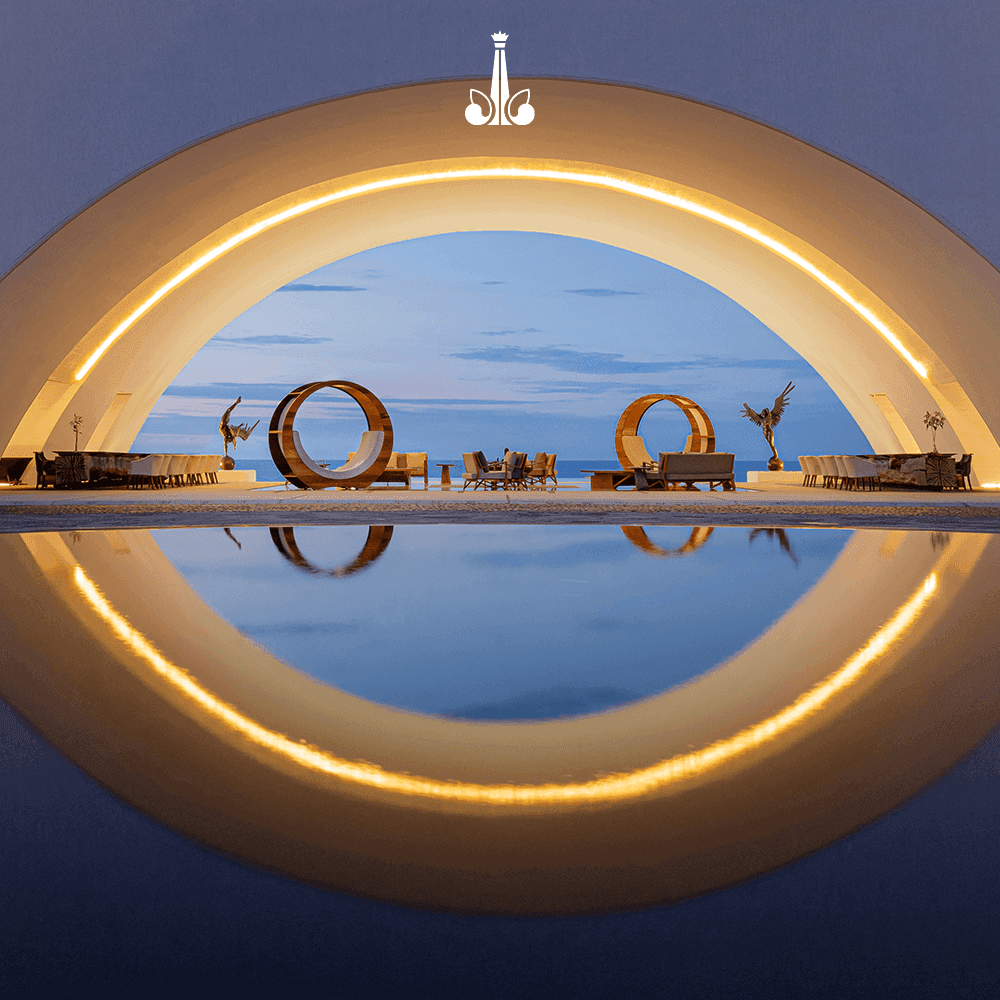 Illuminated outdoor lounge and event space featuring artistic sculptures at Marquis Los Cabos Resort