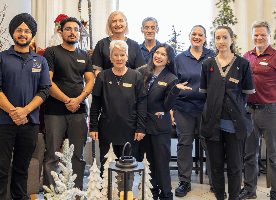 Proud hotel team standing together by festive holiday decorations and trees in a lounge at Rodd Hotels & Resorts