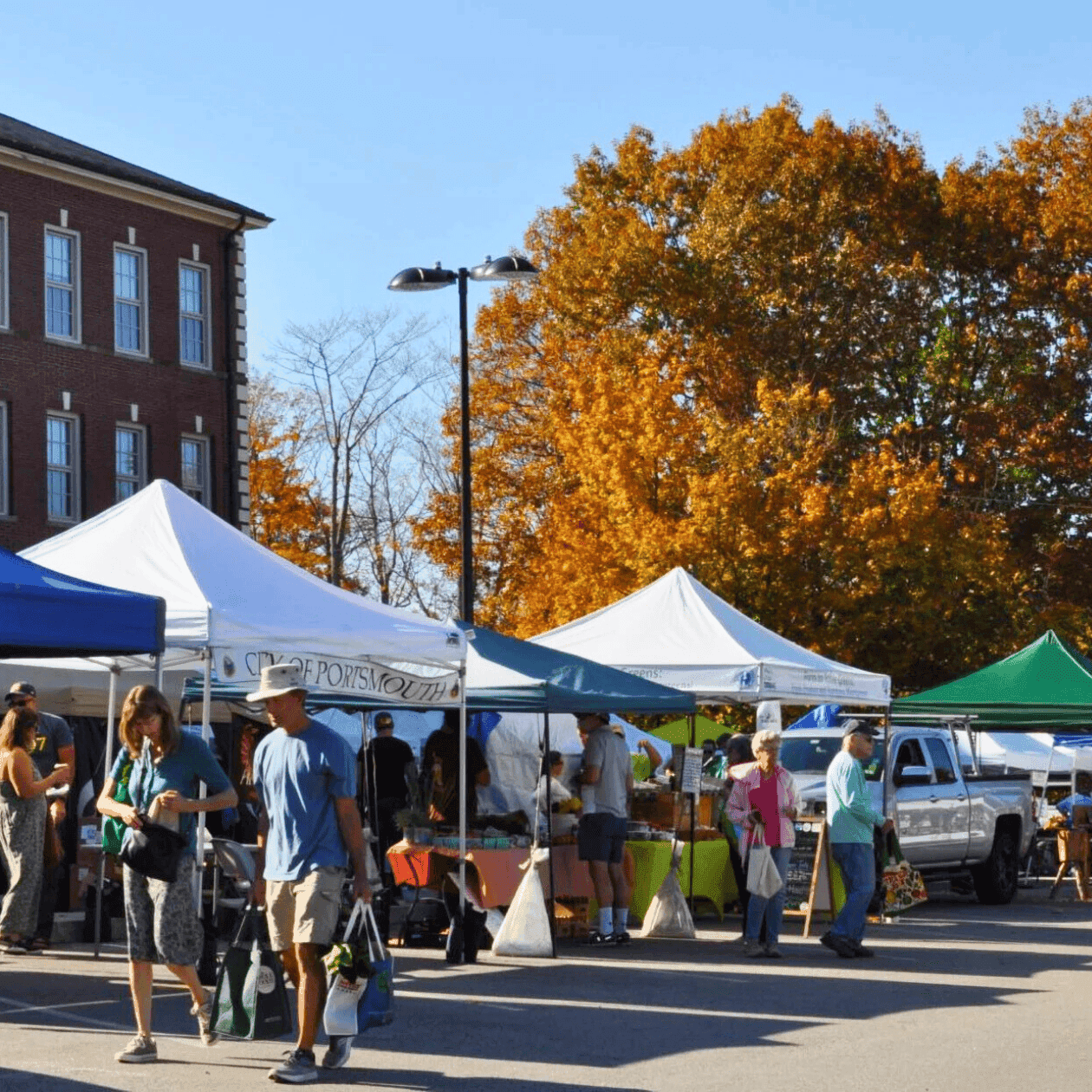 Crowded winter market with tents selling locally grown produce and goods under a blue sky.