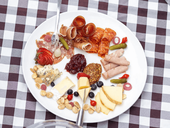 Plate with meats, cheeses, and fruit on a checkered tablecloth at the inn at willow grove