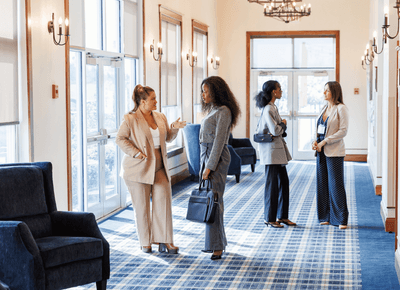 Business guests networking in a bright hallway with blue seating and large windows at Rodd Crowbush Golf & Beach Resort