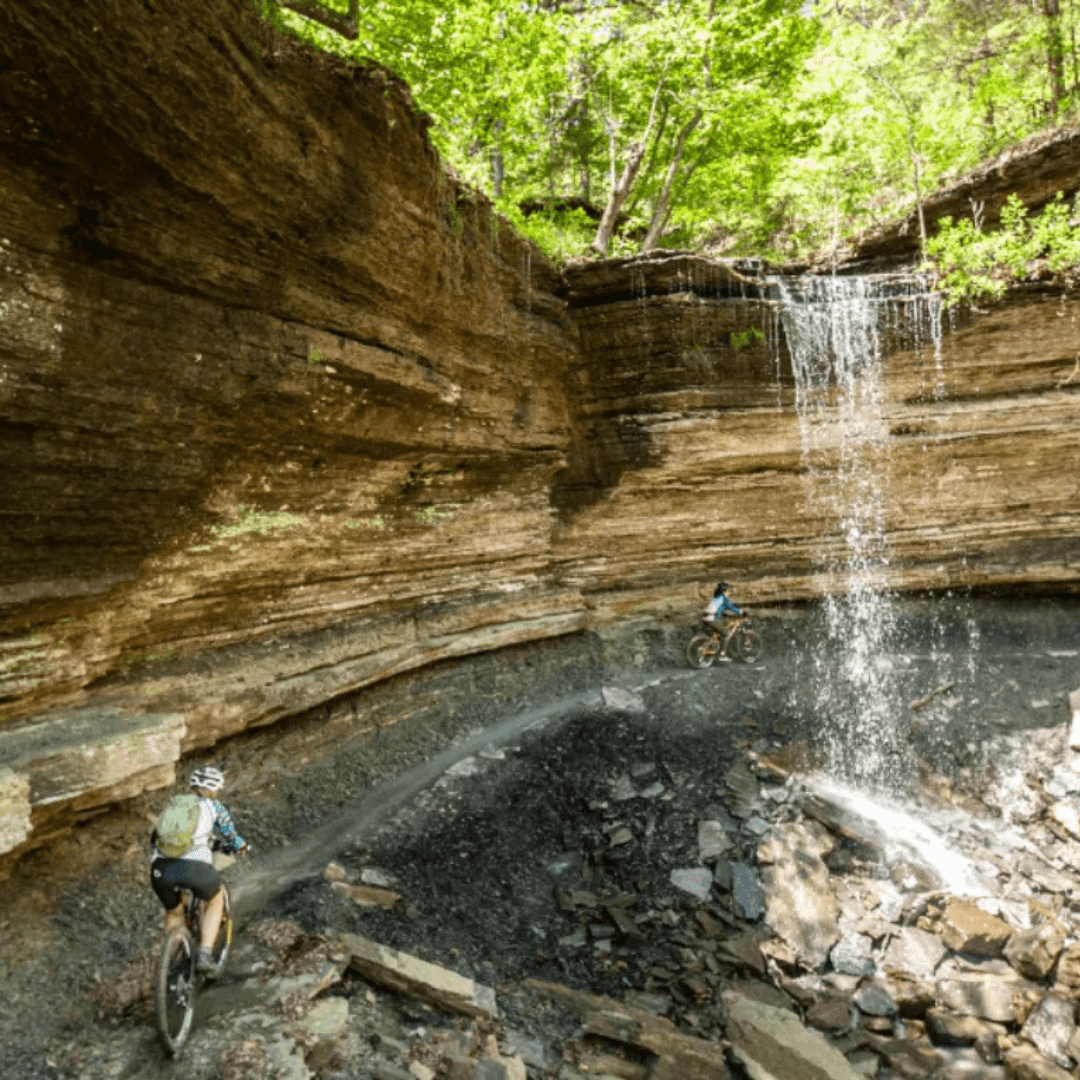 Cyclist riding through a mountrian path through a waterfall in the forest of Arkansas 