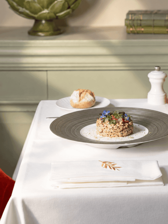 Elegantly plated risotto dish with edible flowers on white tablecloth at Le Céladon, Hôtel Westminster - Paris