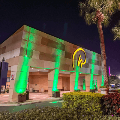 Green lights beaming on a nighttime view of Rosen Inn International.