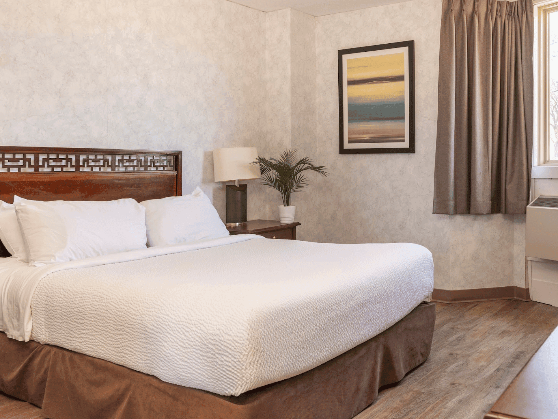 Nightstand by the cozy bed in the Standard King room with wooden flooring at Rodd Grand Yarmouth