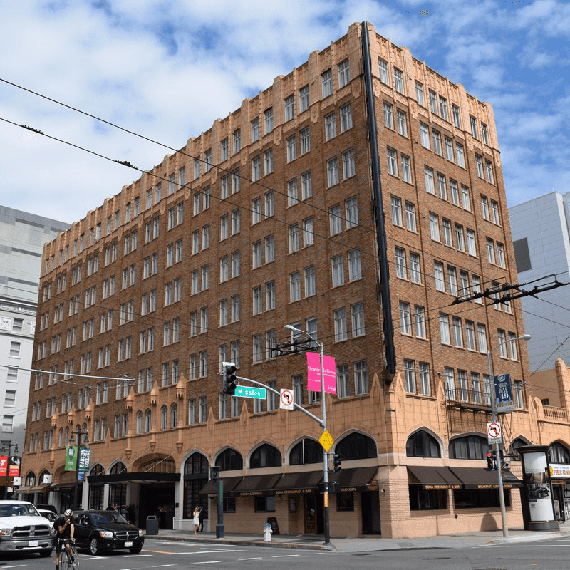 Multi-story brick hotel building with many windows and street view at Pickwick San Francisco