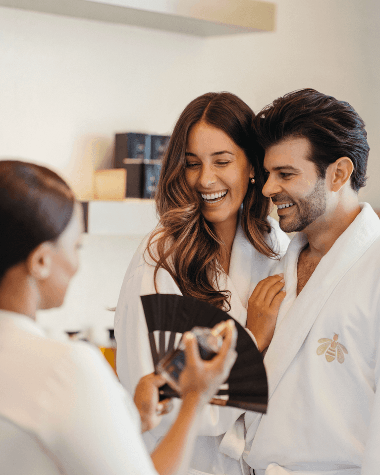 Spa attendant fanning scents by a laughing couple in white robes under soft ambient lighting at Hotel X Toronto