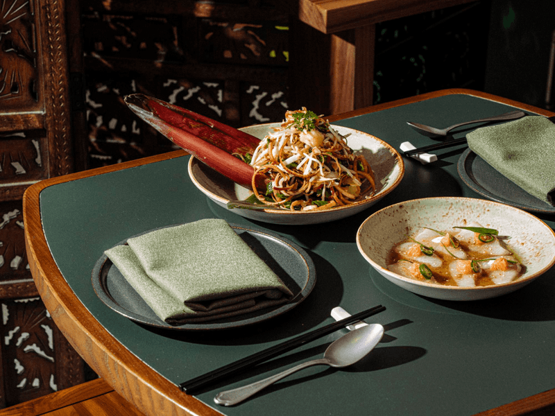 Two seafood dishes with chopsticks and napkins on a green table for Easter Seafood Banquet at Delta Rue.