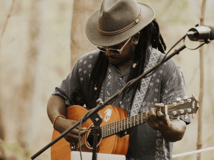 musician playing guitar in woods