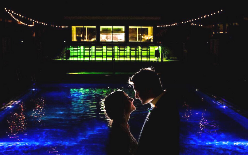 Bride and groom take a photo near the pool at night at our Avalon wedding venue