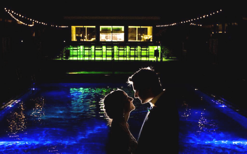 Bride and groom take a photo near the pool at night at our Avalon wedding venue