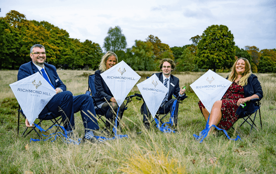 Four people sitting with kites on their hands at Richmond Hill