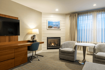 Guest room sitting area with fireplace, television, desk, chairs, and table at Anchorage By The Sea