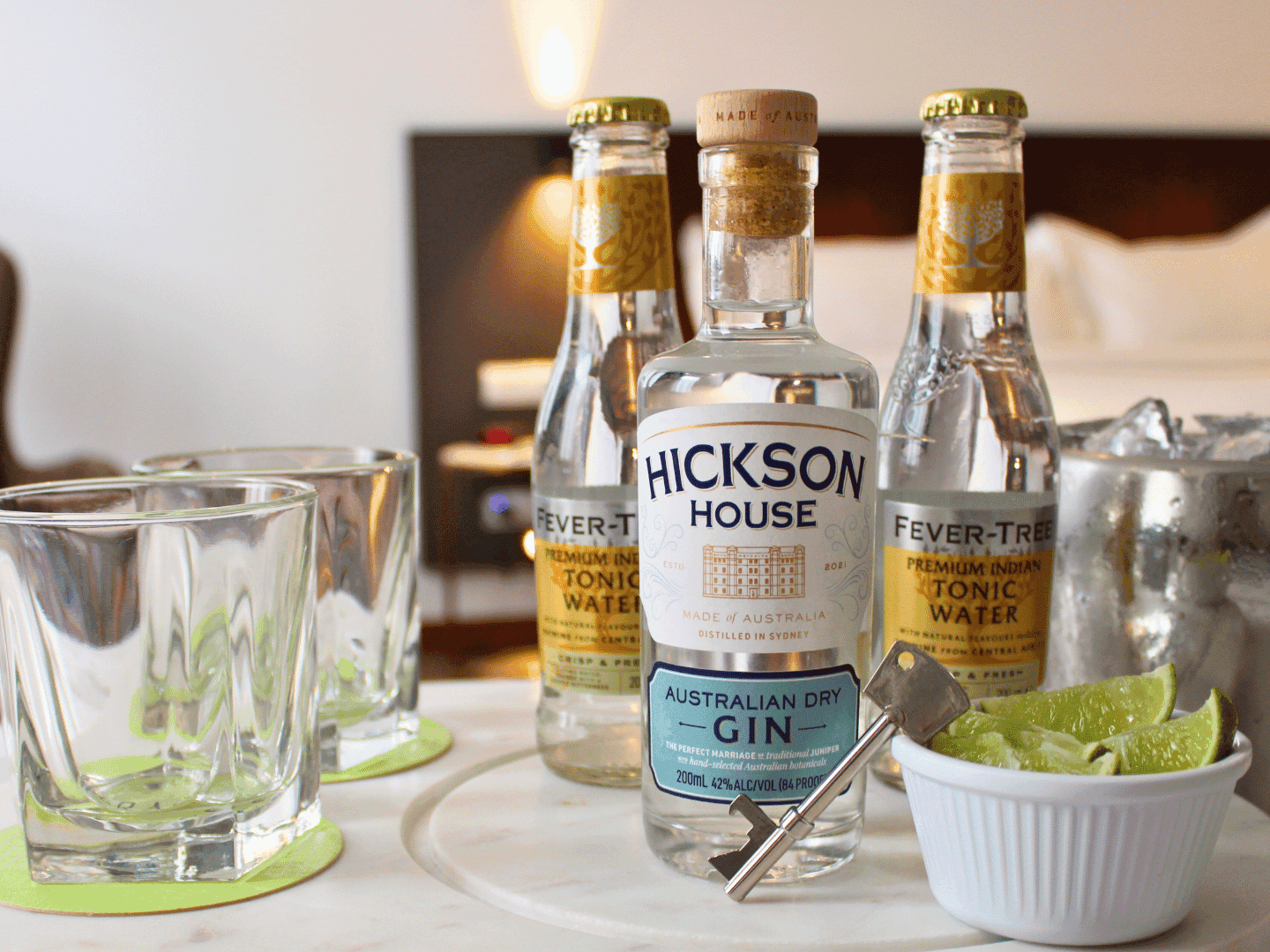 Bottles of tonic water and gin with empty glasses and sliced limes on a table at Federal Hotels International