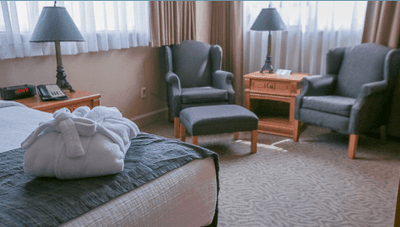 Seating area by the bed with sofas and furniture in the Business Suite at The Glenmore Inn & Convention Centre