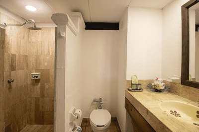Bathroom with shower, toilet, sink, and mirror, featuring tiled walls and wooden cabinetry.