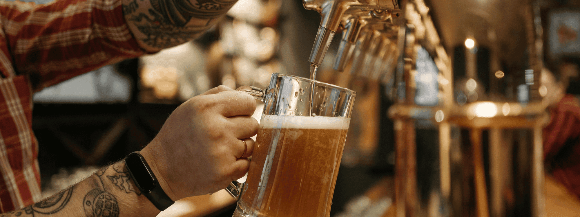 Close-up of a bartender pouring frothy beer from a tap into a glass mug at Novotel Sydney International Airport