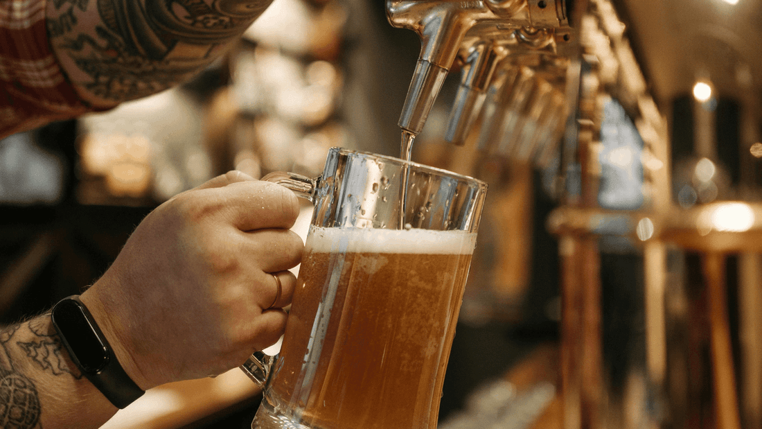 Close-up of a bartender pouring frothy beer from a tap into a glass mug at Novotel Sydney International Airport