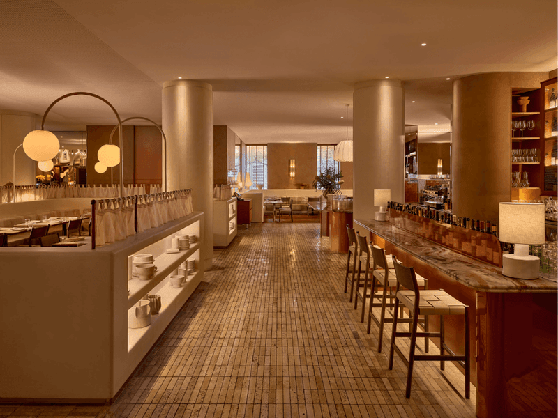 Elegant restaurant interior with bar, chairs, and dining tables under modern lighting.