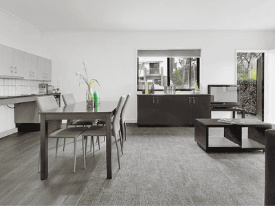 Modern open-plan living area with dining table, kitchen, and dark wood furniture at Springfield Central