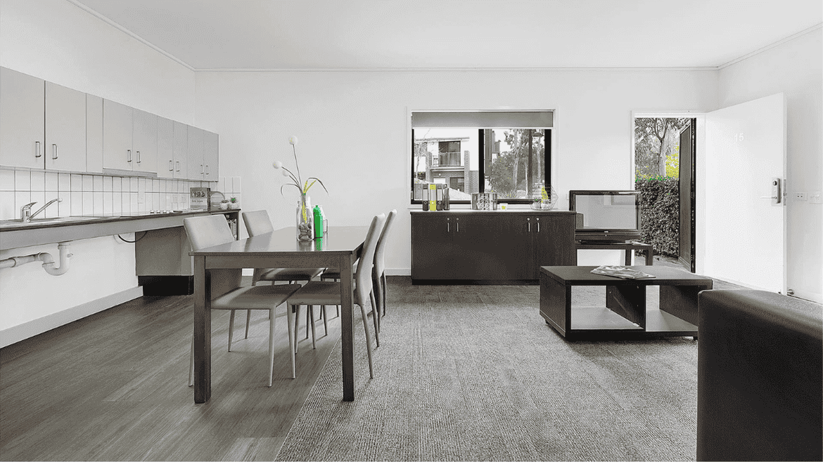 Modern open-plan living area with dining table, kitchen, and dark wood furniture at Springfield Central