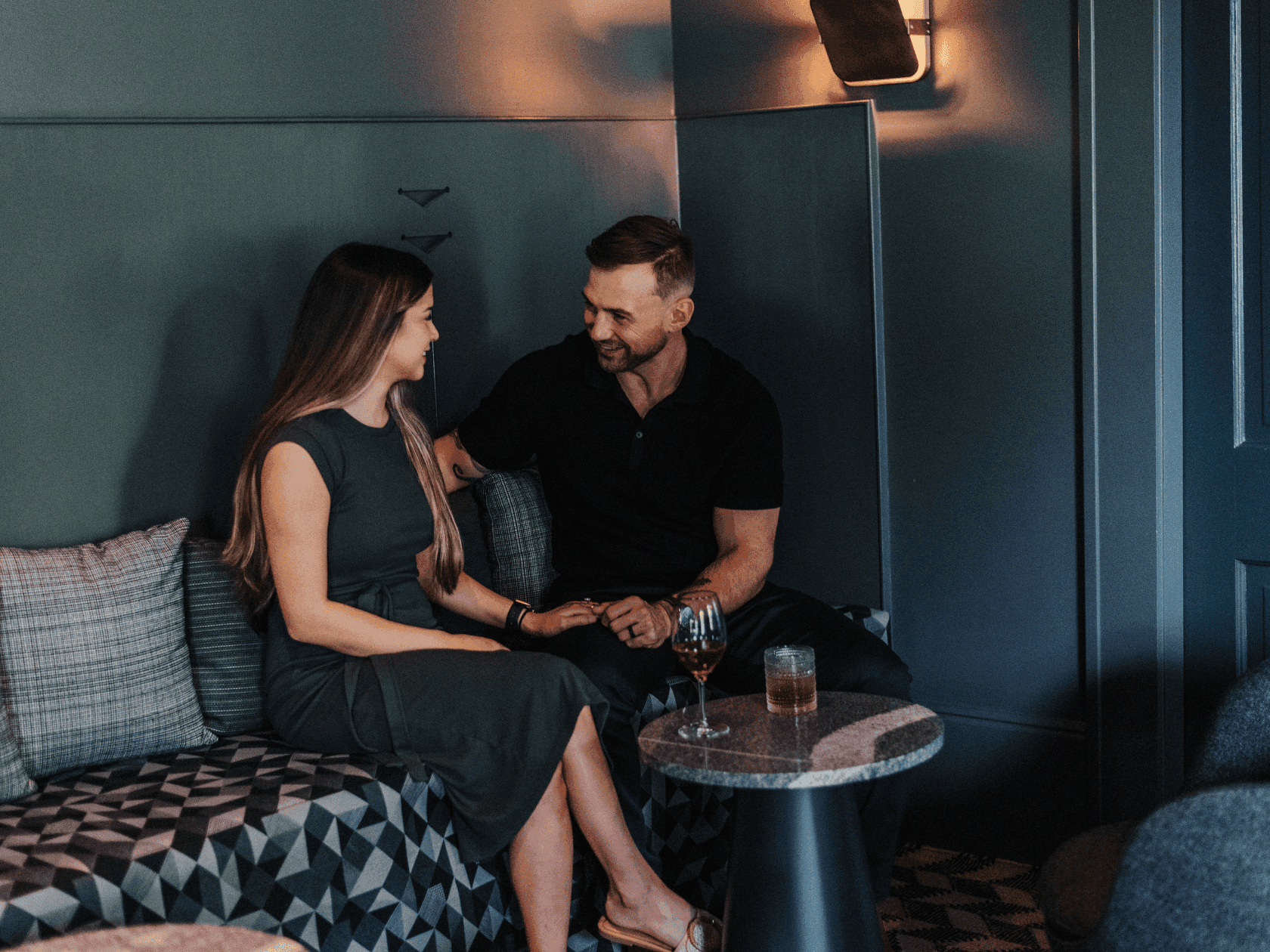 Couple sitting together in a cozy lounge setting with wine glasses, promoting the Valentine Sweetheart Stay.