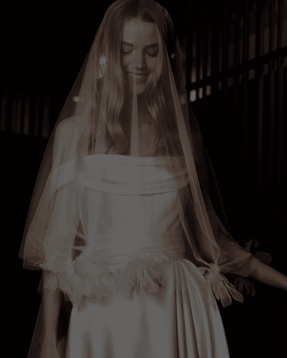 A beautiful bride in a flowing white gown and veil, smiling gently within The Londoner Hotel's elegant ambiance