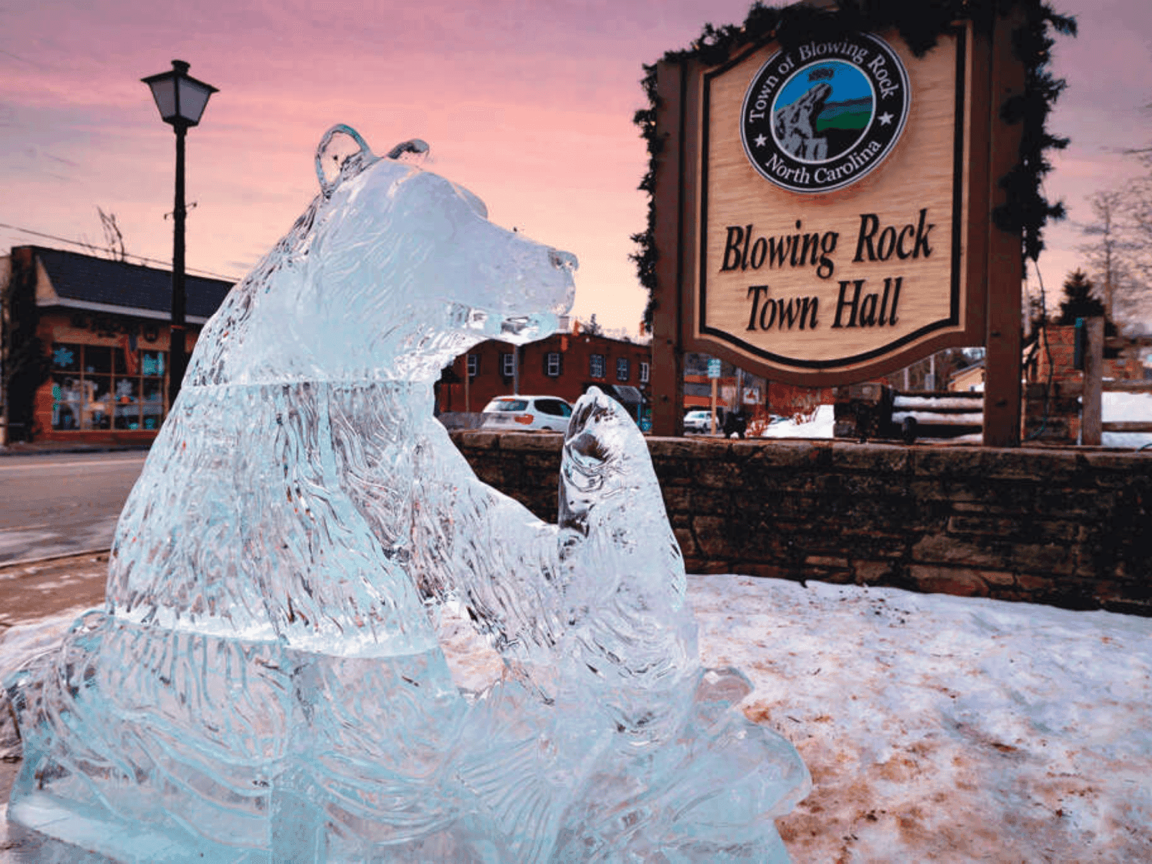 Ice sculpture of bear and cub in front of Blowing Rock Town Hall sign at sunset.